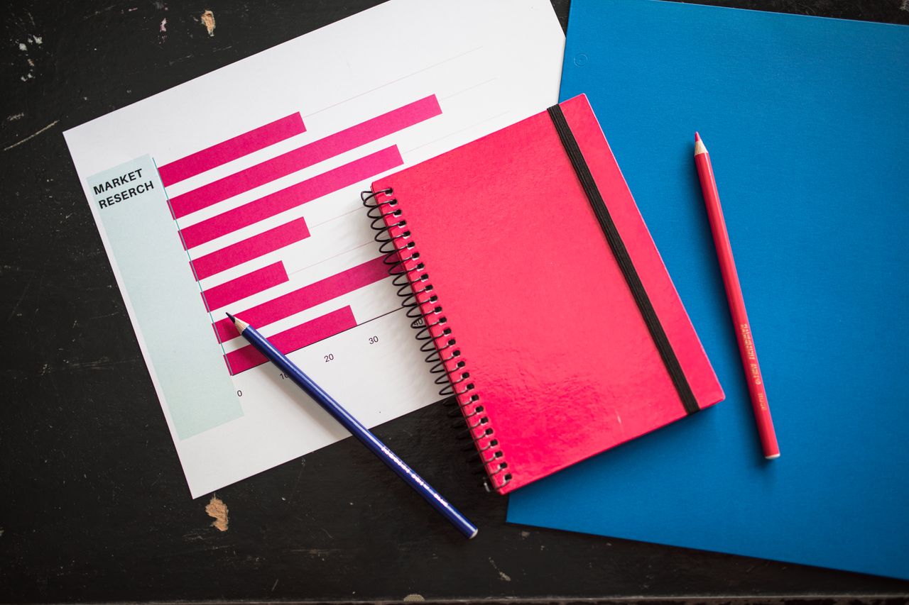 why-choose-us Overhead view of business chart with red notebook and colored pencils on table.